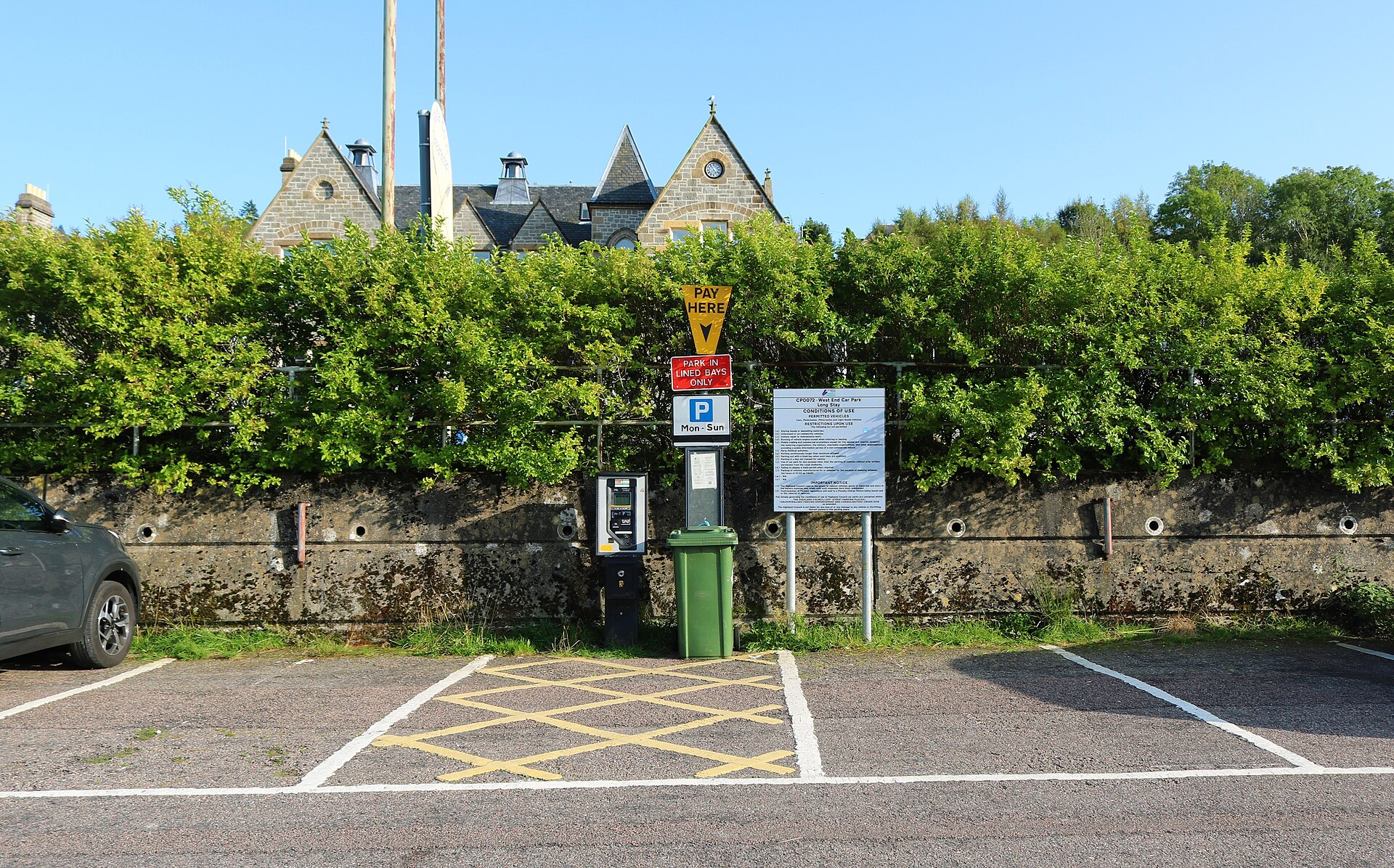 A pay-and-display machine and parking signs at a UK car park