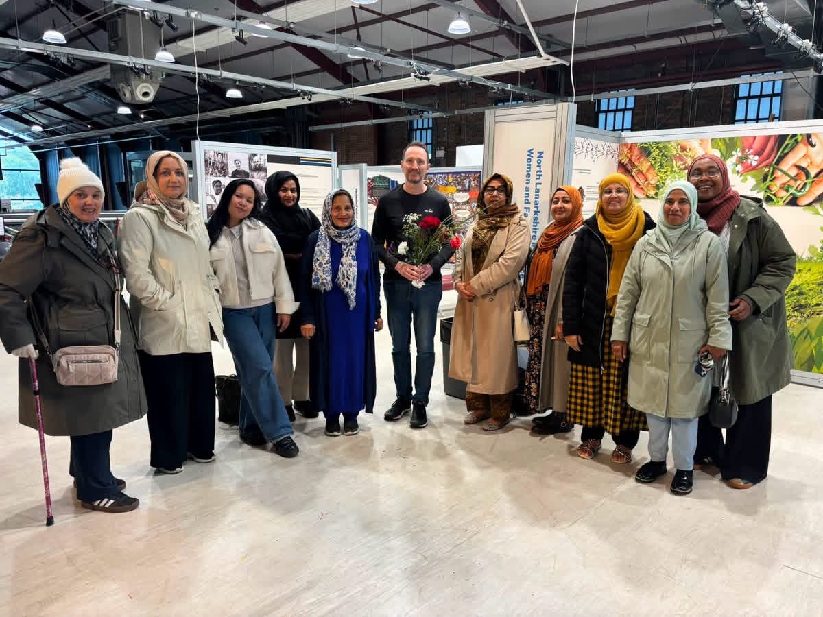 Fulton MacGregor MSP holding flowers with NLMWA members at the Traces of Empire exhibition in Summerlee Museum, Coatbridge