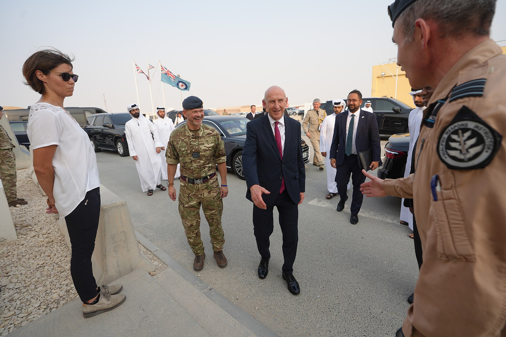 John Healey in a suit walking with military personnel at an airbase