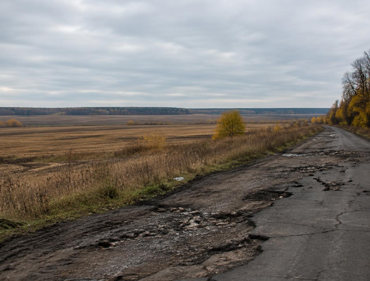 Illustrative image of farmland and a damaged rural road