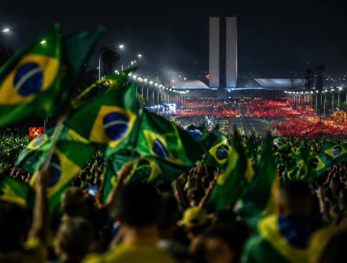 Crowds waving Brazilian flags at night on the avenue leading to Congress in Brasilia