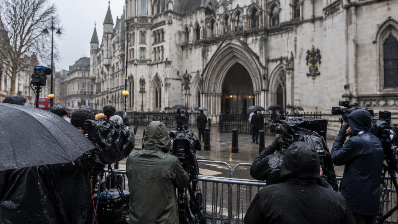 Illustrative press photographers and camera crews outside a London court in the rain