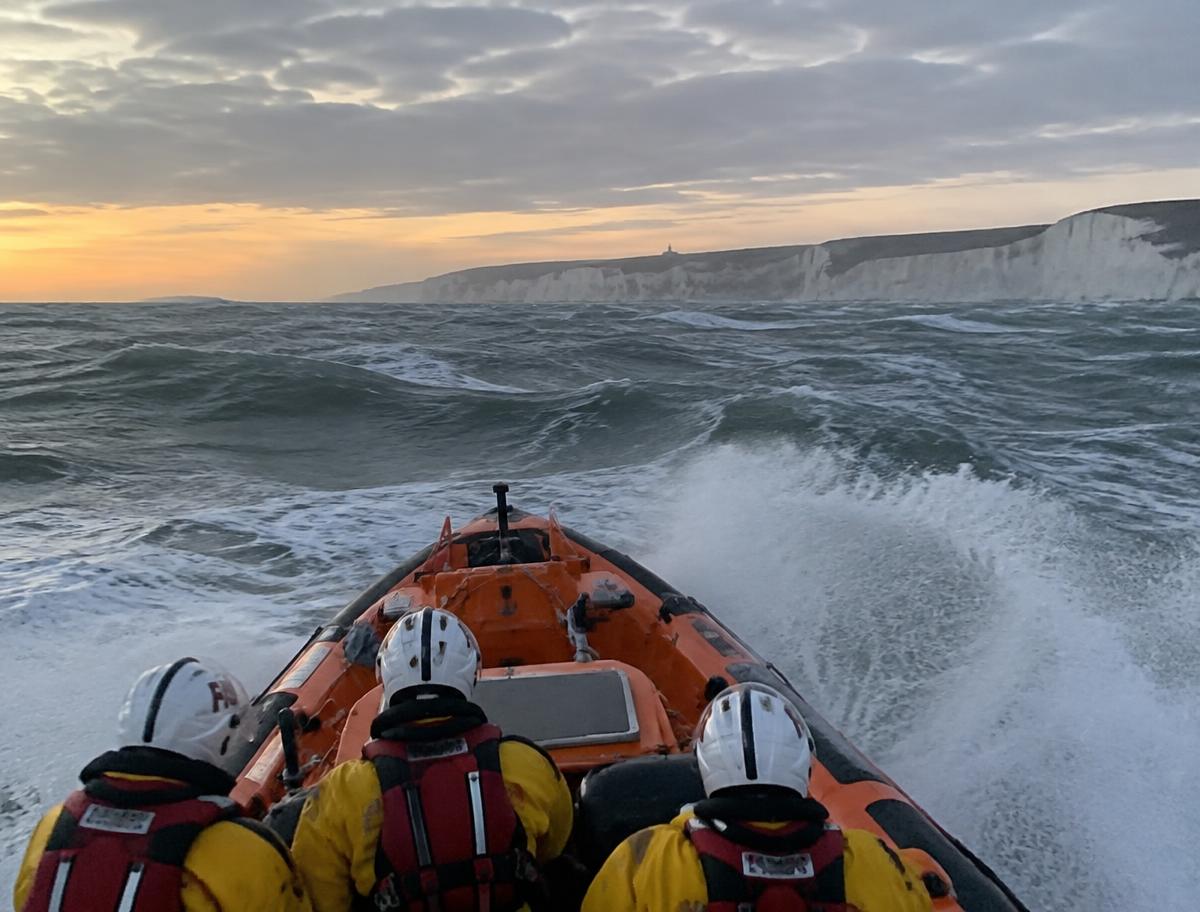 Illustrative lifeboat crew powering through Channel swell beneath white cliffs